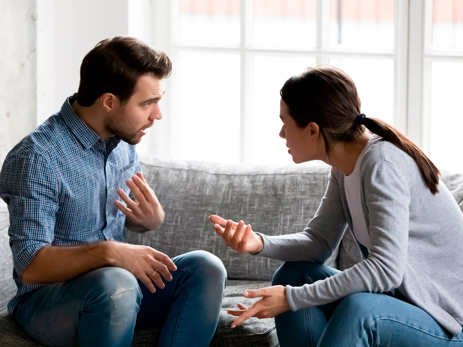 Casal conversando de forma tensa no sofá